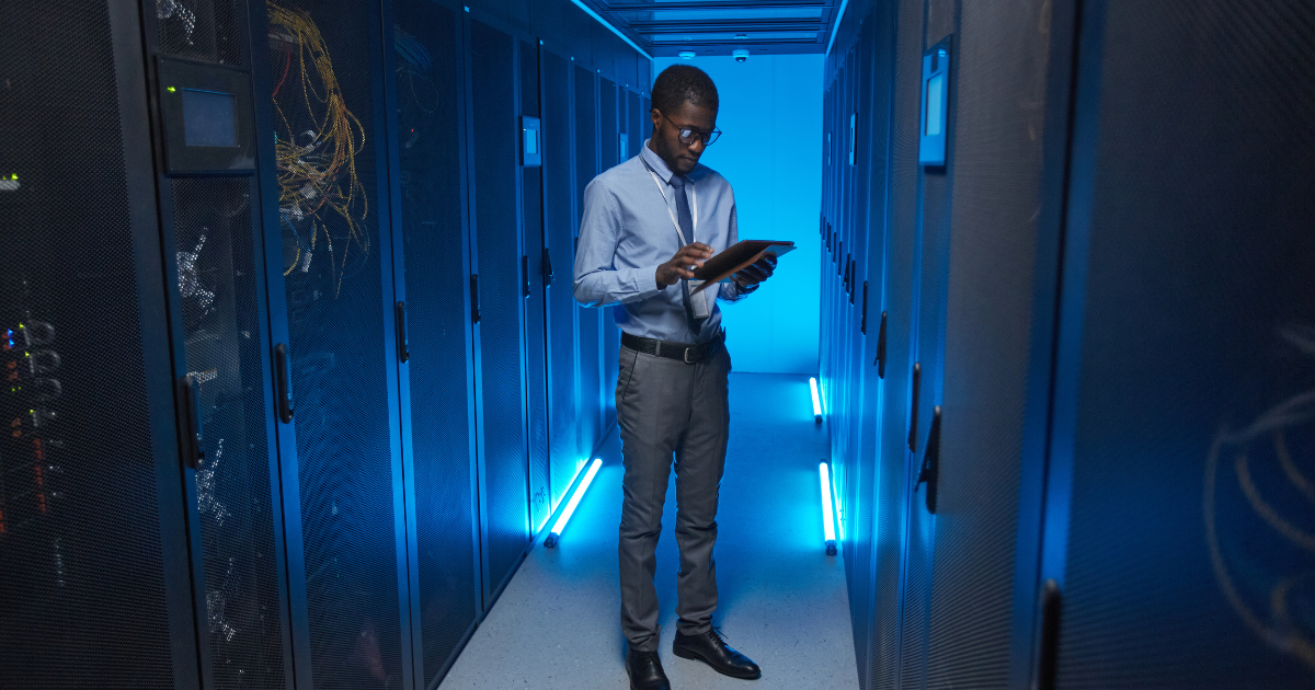 homem utilizando tablet em data center para monitorar infraestrutura protegida por no-break senoidal puro