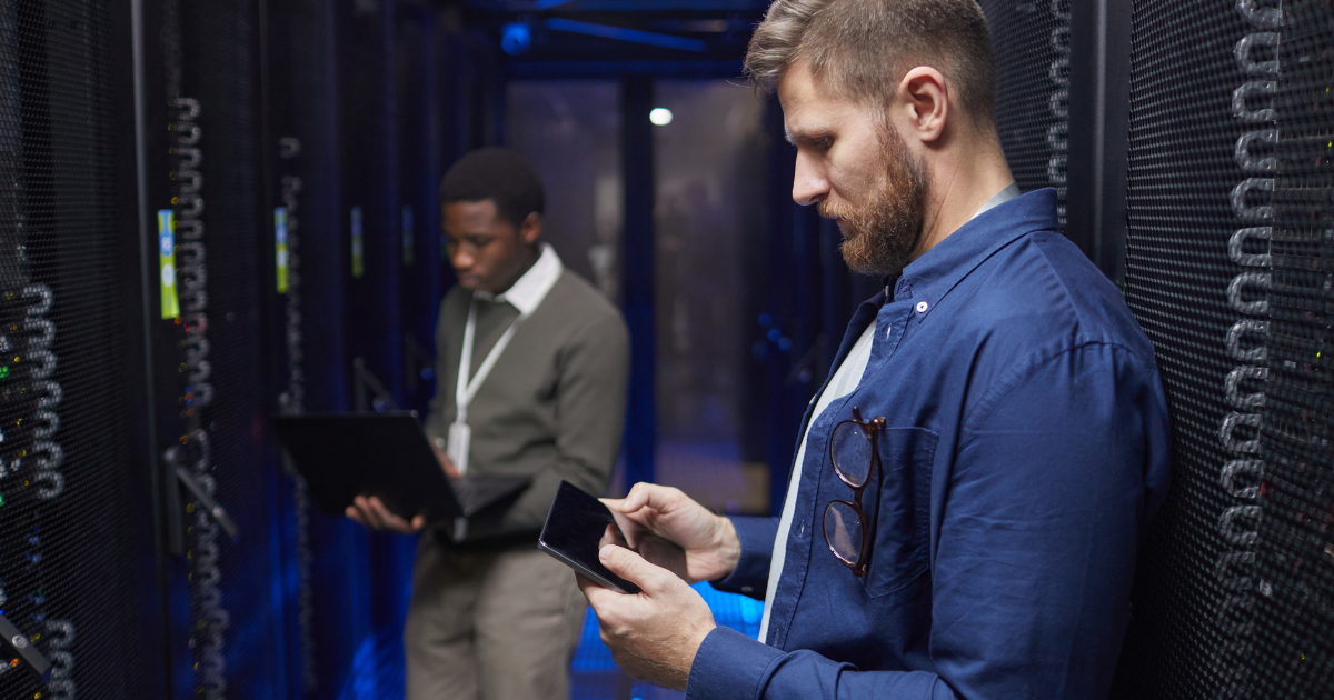 dois profissionais analisando servidores em um data center para garantir a continuidade operacional e a eficiência da infraestrutura de energia crítica.